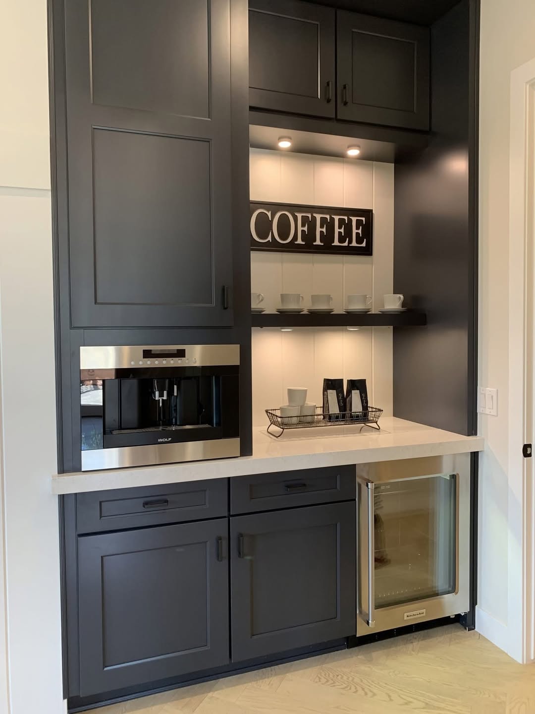 Charcoal grey cabinets with a built-in coffee machine and white quartz counter