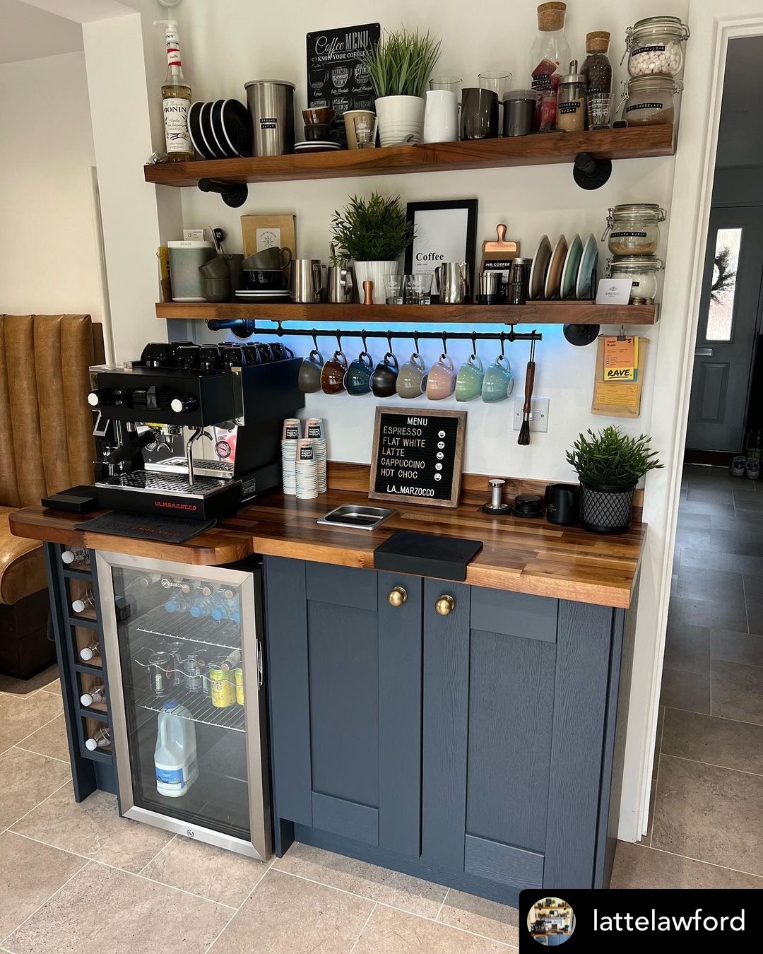 Navy blue coffee bar with wood counter, espresso machine and hanging mug rail