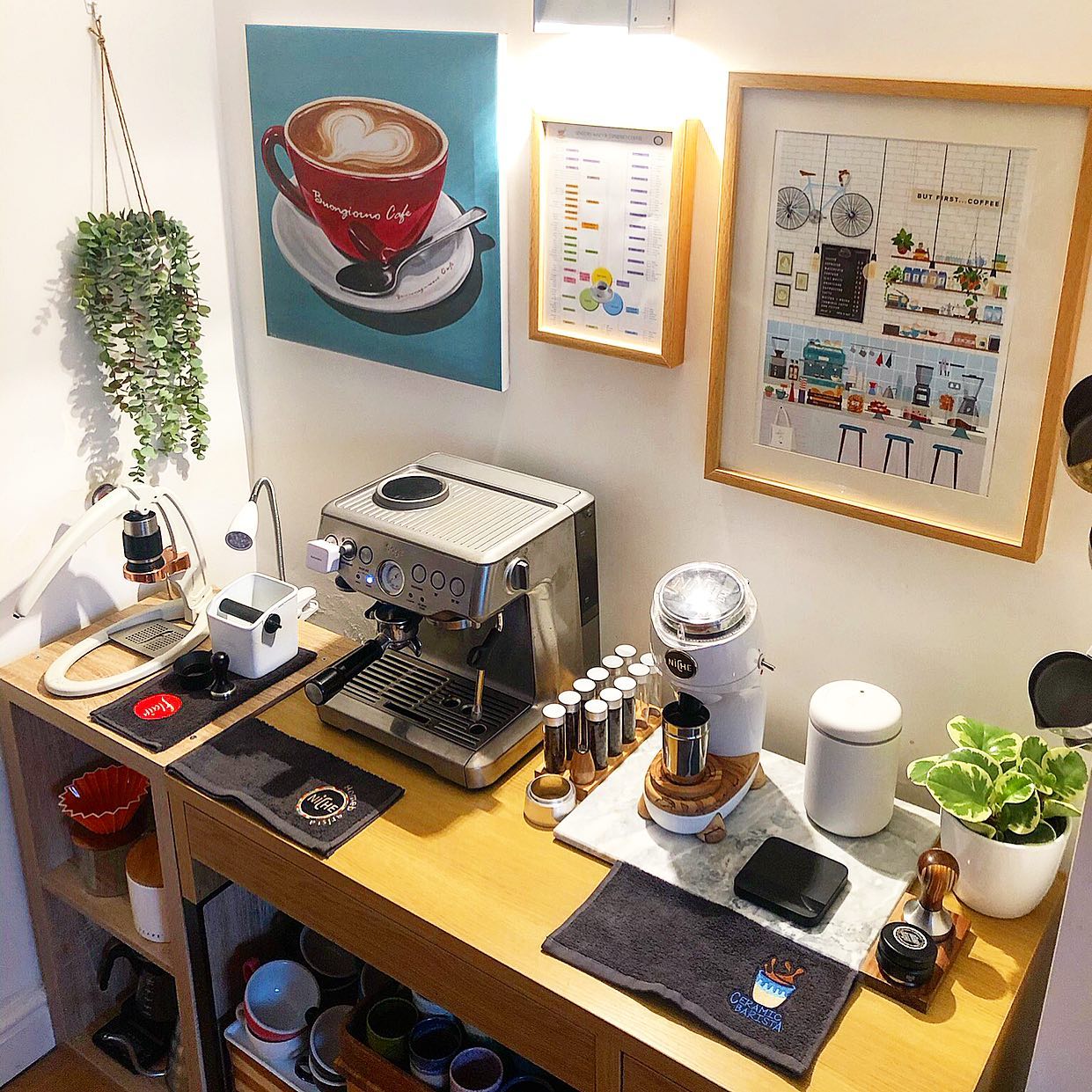 Home espresso setup on a wood table under a wall of framed coffee prints