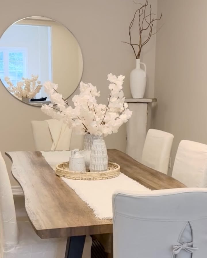 Olive branches in a white textured vase on an oval light wood dining table