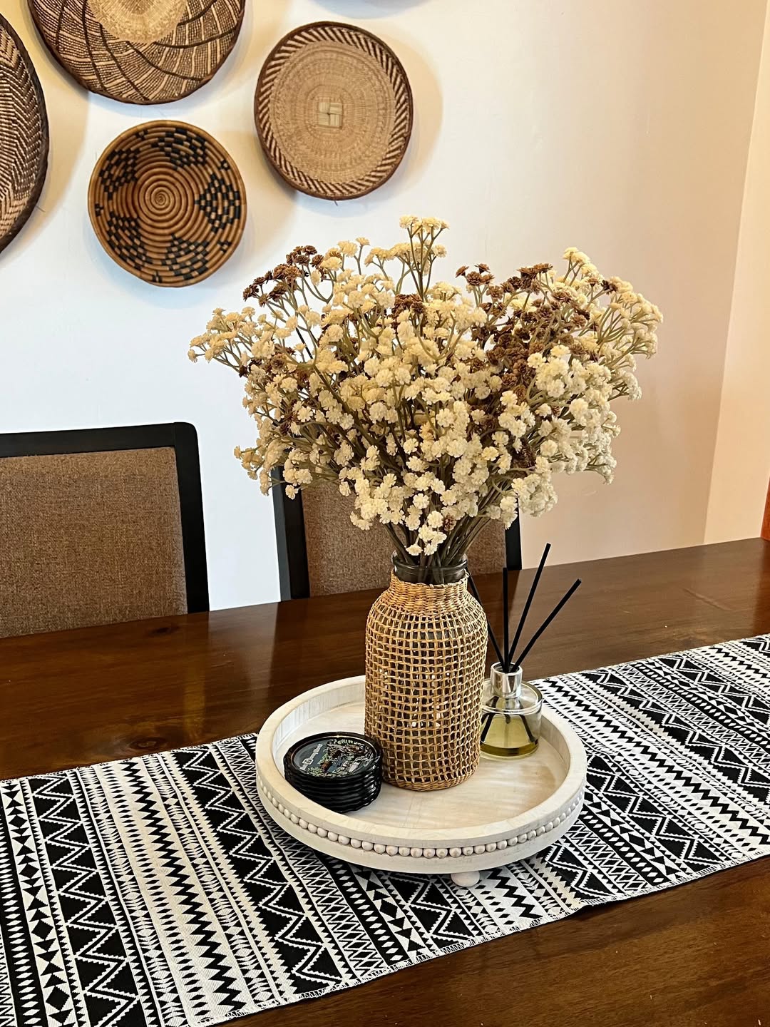 Cream roses in a white vase with amber candles on a round marble dining table