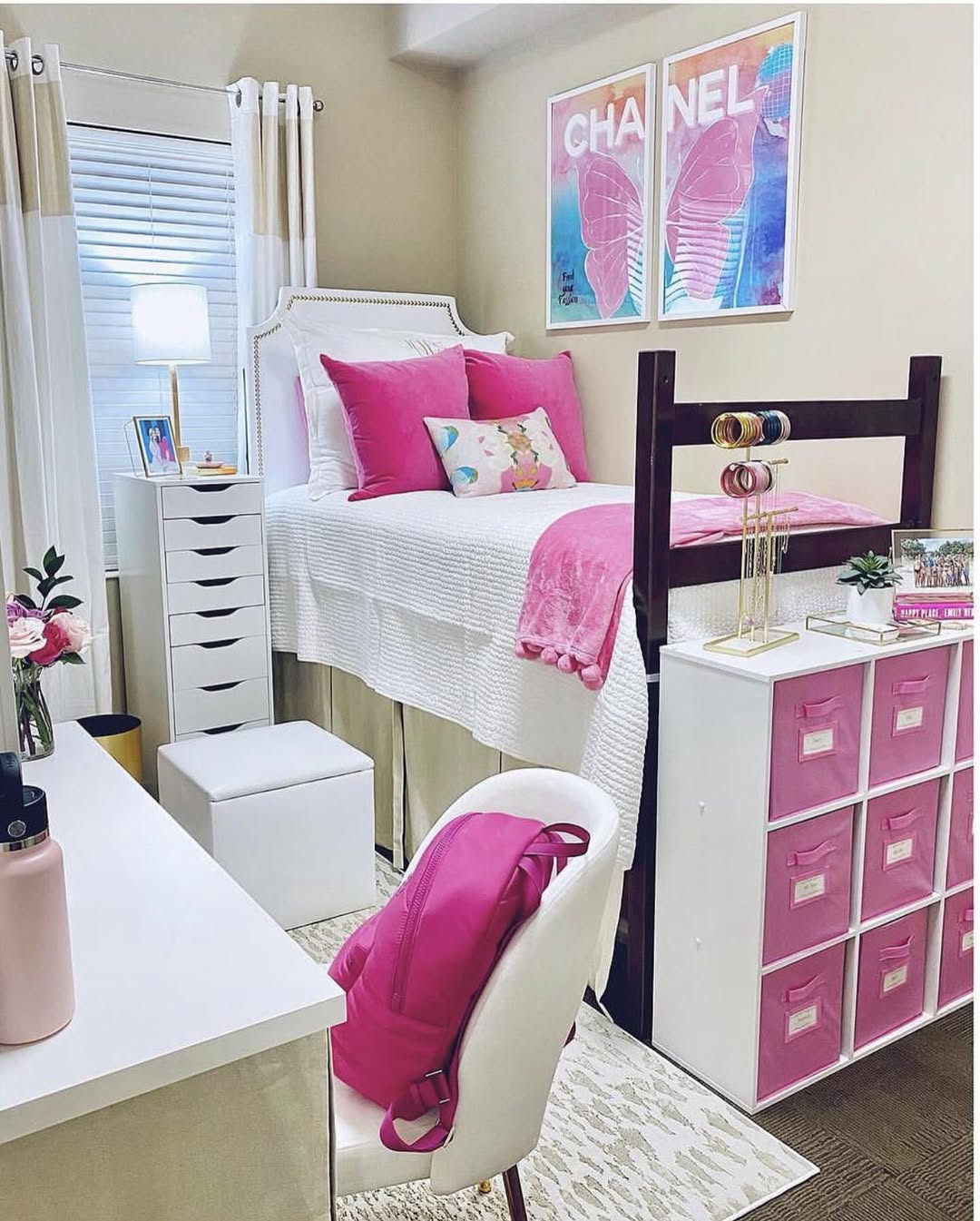 Lofted dorm bed with hot pink velvet pillows, Chanel butterfly art, and pink storage bins