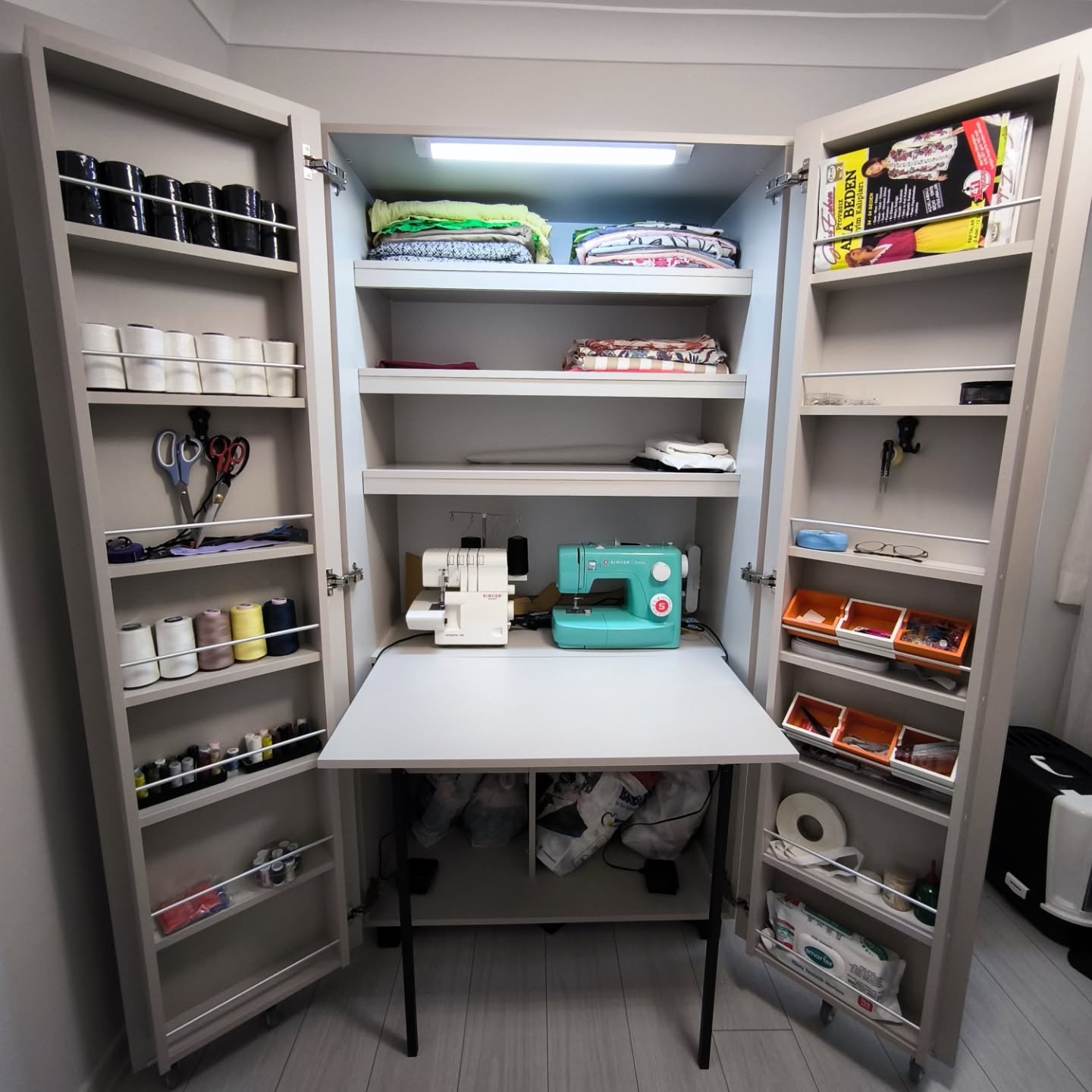 Taupe cabinet system with a drop-down sewing table and thread racks